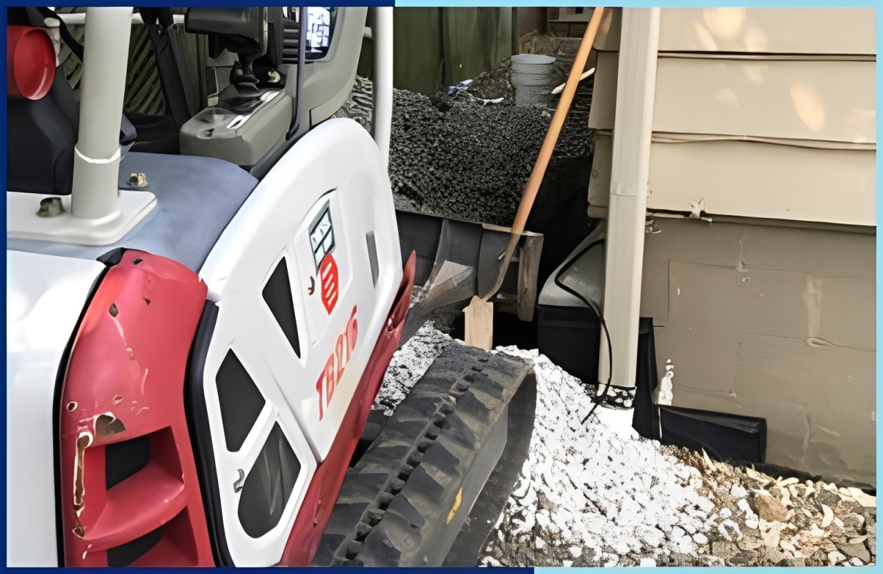Mini excavator positioned on gravel near a house foundation