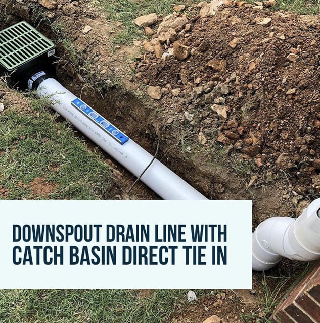 Downspout drain line connected to a catch basin, shown in a dug trench on grass.